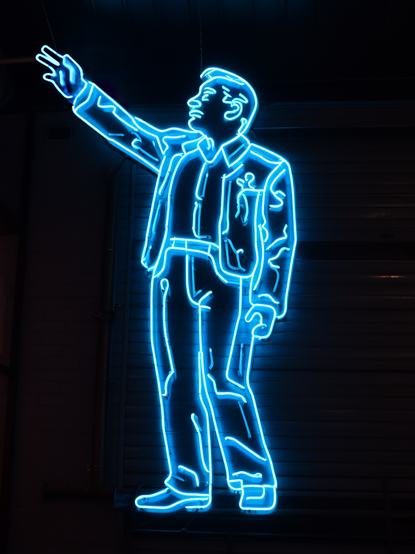 K.I.-generiertes Bild einer aus Neonröhren geformten, blau leuchtenden Männerfigur auf schwarzem Hintergrund mit erhobenem rechten Arm