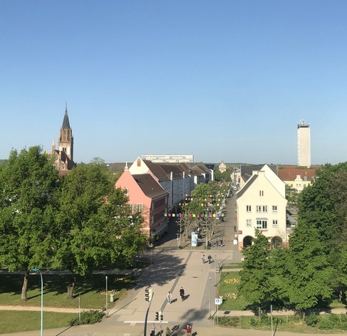 Blick auf die Fußgängerzone, Konzertkirche und moderner Aussichtsturm schauen über Häuser und Bäume hinaus.