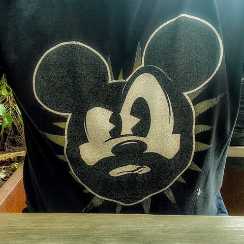 Brustbild-Selfie: der Frontprint des schwarzen Shirts zeigt das gezeichnete Gesicht von Micky Maus, der Gesichtsausdruck ist kritisch bis skeptisch, und als Besonderheit hat Micky einen schwarzen Vollbart 