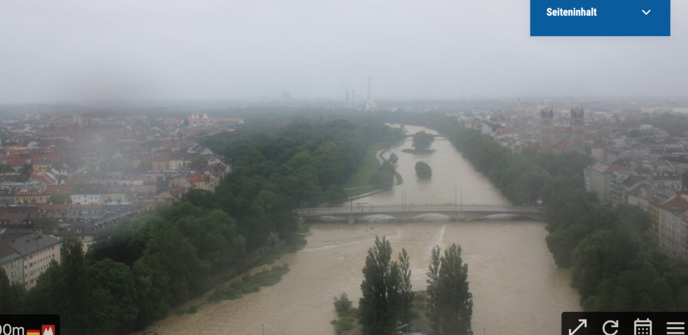 Webcam-Aufnahme von Fluss in Stadt, hellbraunes Wasser, die Uferwege sind überschwmmt
