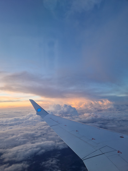 Flug über der Wolkendecke, Tragfläche und Abendsonnenlicht am Horizont