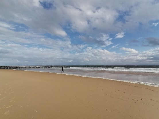 Am Strand, wo der Mann am Saum der Wellen heumspaziert.