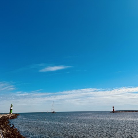 Blick von der Westmole auf die Hafenausfahrt, flankiert durch beide Molenfeuer, blauer Seeksnal, blauer Himmel, weiße Wölkchen