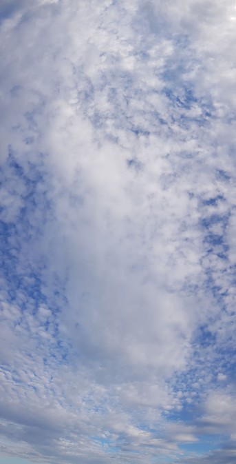 Panorama hochkant, Schäfchenwolkenschicht, darunter größere Wattewolken, drüber Blauhimmel