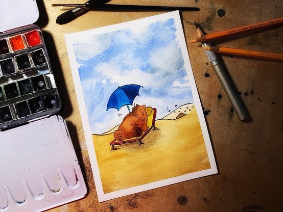 Aquarellbild, das den sich eincremenden Bären auf einer Strandliege unter einem blauen Sonnenschirm zeigt. Um das Gemälde herum befinden sich ein Farbpalette, Pinsel, und Farbstifte. Im Hintergrund entsteht gerade ein Maulwufshügel.