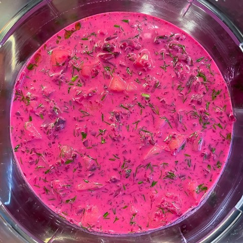 Blick von oben in eine Schüssel mit leuchtend rosa Rote-Bete-Suppe, man erkennt darin gehacktes Gemüse und Dill.