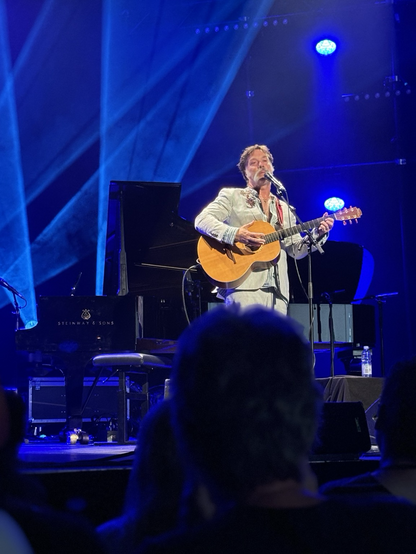 Rufus Wainwright steht mit einer Gitarre alleine auf der Bühne und singt. 