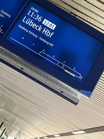 Schräge Aufnahme von der Abfahrtstafel am Gleis vom Bahnhof Hannover, die als Fahrtziel Lübeck anzeigt. 
