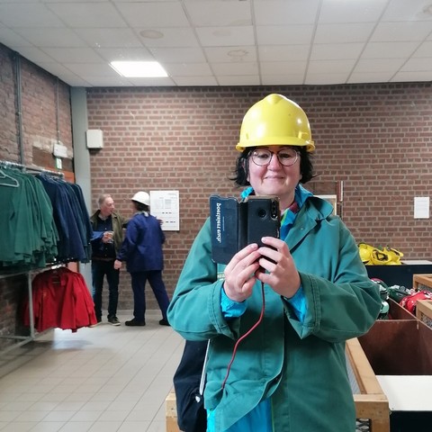 Ich wurde mit gelbem Schutzhelm und grünem Bergmannkittel ausgestattet und mache sofort ein Selfie im Spiegel. 