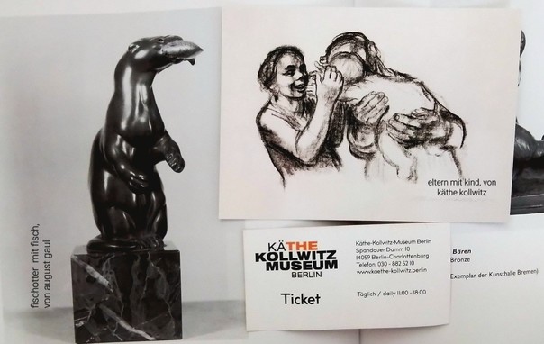 Fotokollage, sie zeigt eine bronzefigur einer stehenden fischotters mit fisch in der schnauze, von August Gaul. Rechts daneben eine ansichtskarte von käthe kollwitz' Eltern mit Kind. Darunter eine aktuelle Eintrittskarte vom käthe kollwitz museum Berlin.