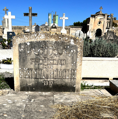 Grabstein auf wenig grünem Friedhof, beschriftet mit 