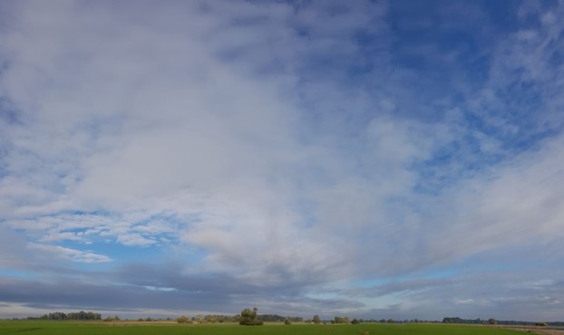 viel grüne Wiesen als schmaler Streifen, darüber jede Menge blauer Himmel mit Wolkenschön