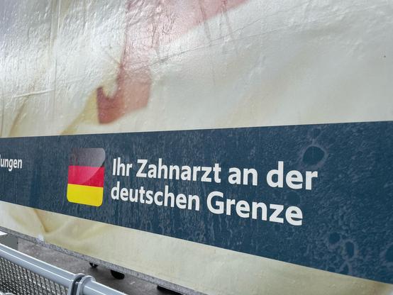 Plakat am Bahnhof Schaffhausen, das Werbung für einen Zahnarzt macht mit: „Ihr Zahnarzt an der deutschen Grenze“.