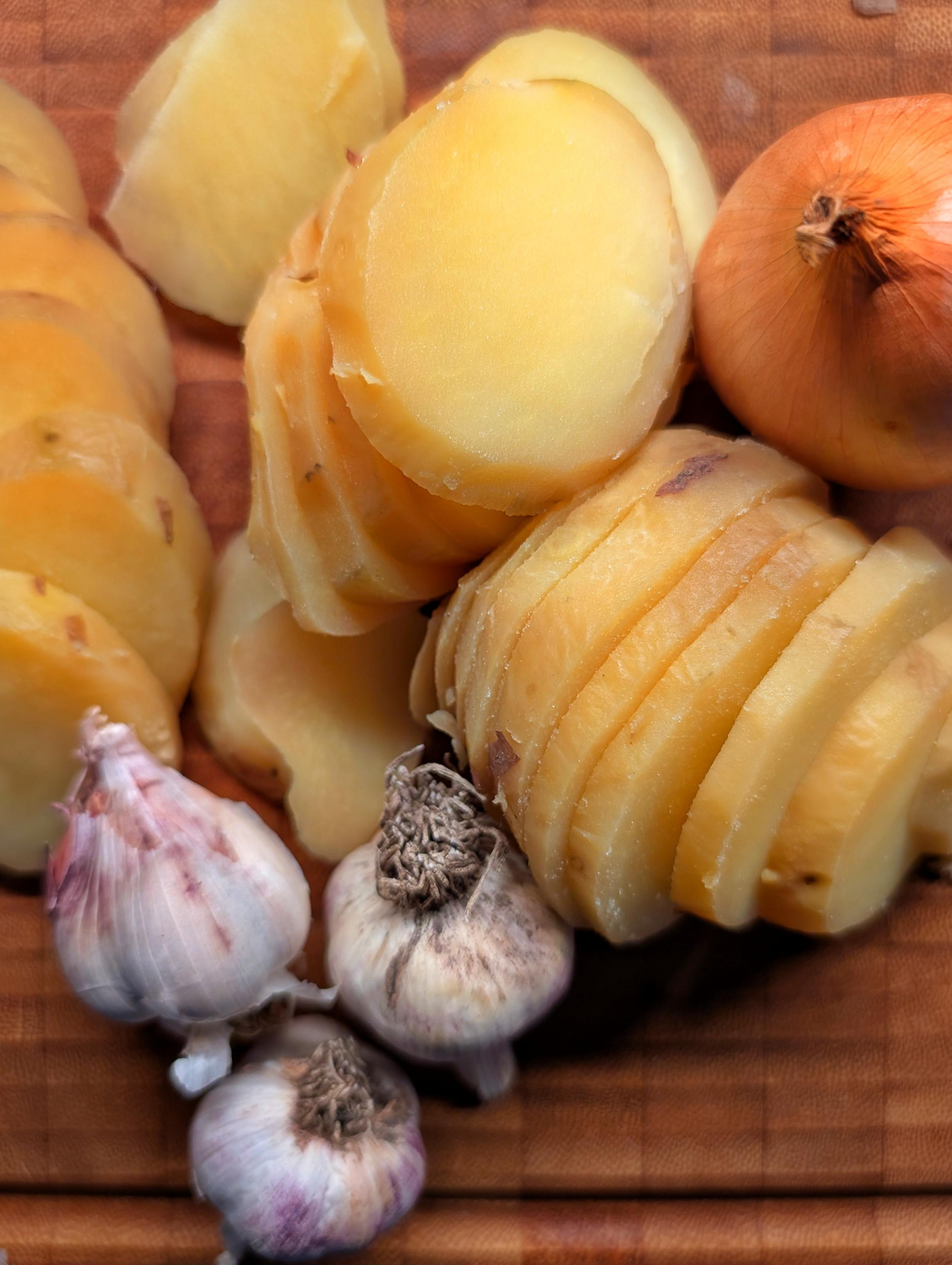 In Scheiben geschnittene Kartoffeln, 1 Zwiebel, drei kleine Knoblauchknollen