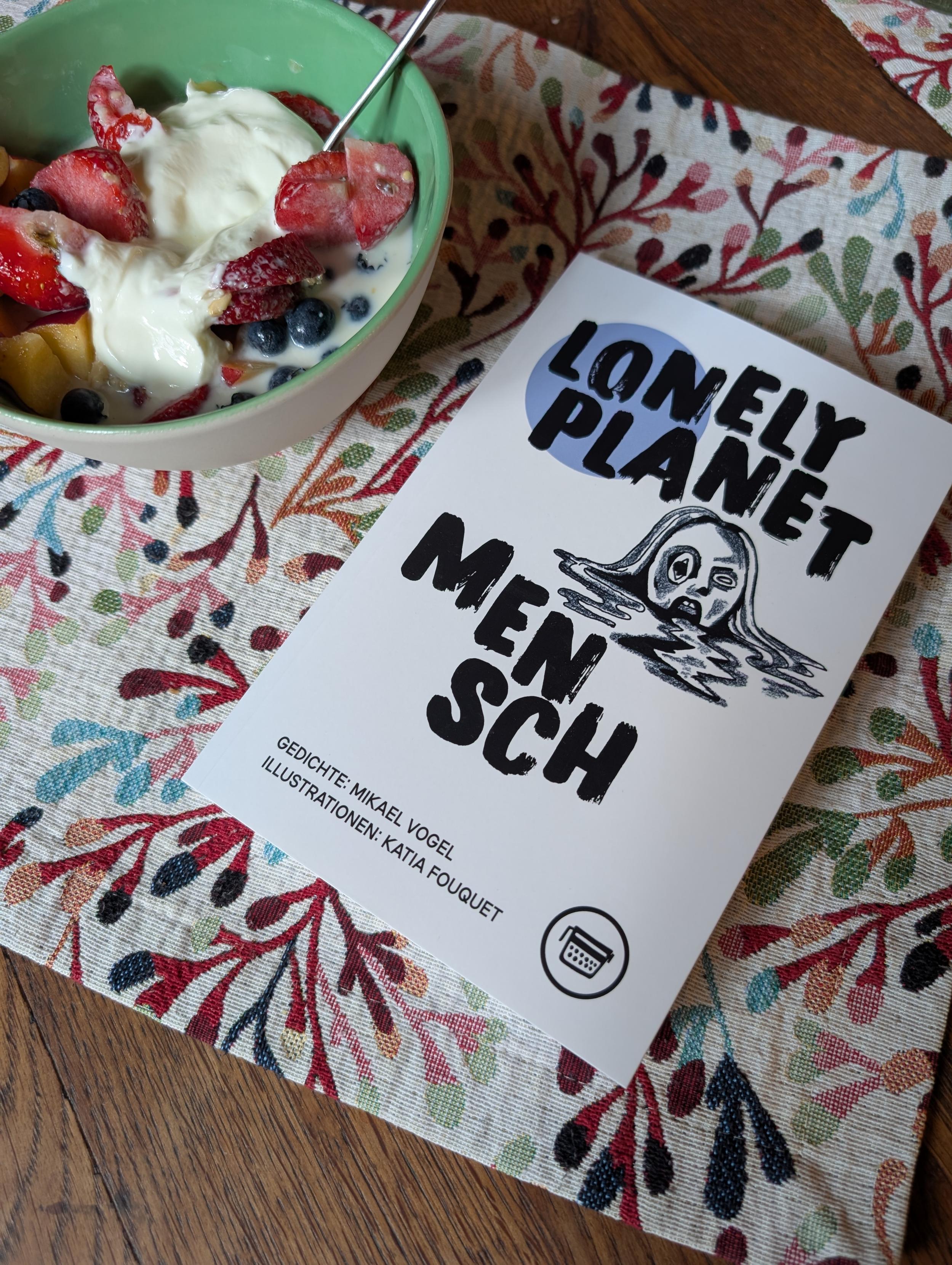 Das Buch neben einer Schüssel mit Overnight Oats und Obst auf einem geblümten Stofftischset.