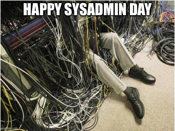 Meme pic of a person stuck in a server rack and messy tangled cables so that only their legs are visible with a caption: HAPPY SYSADMIN DAY