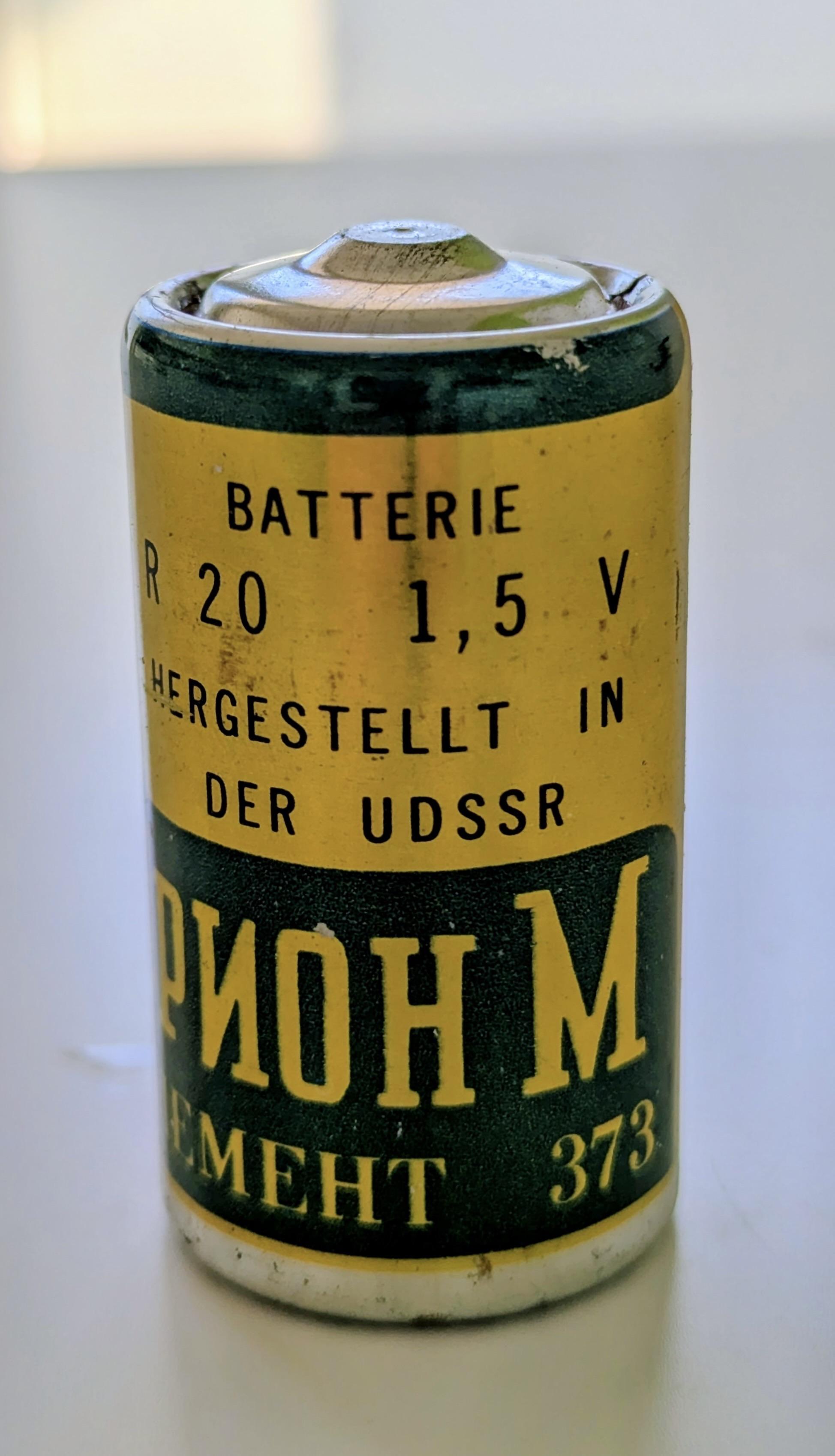 Sehr alte dicke R20 Batterie in grün-gold mit Aufdruck:
Batterie 
R20   1,5V
Hergestellt in der UDSSR
(nun in kyrillischen Buchstaben:)
Orion M
Element 373